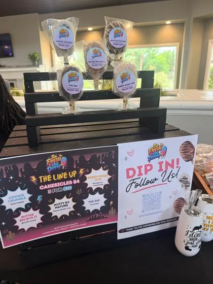 Market display with wrapped cakesicles and the flavor line up sign