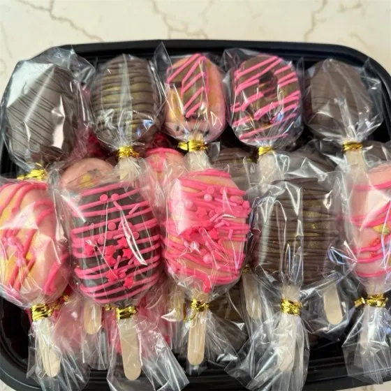 Tray of individually wrapped pink and chocolate cakesicles with gold ties